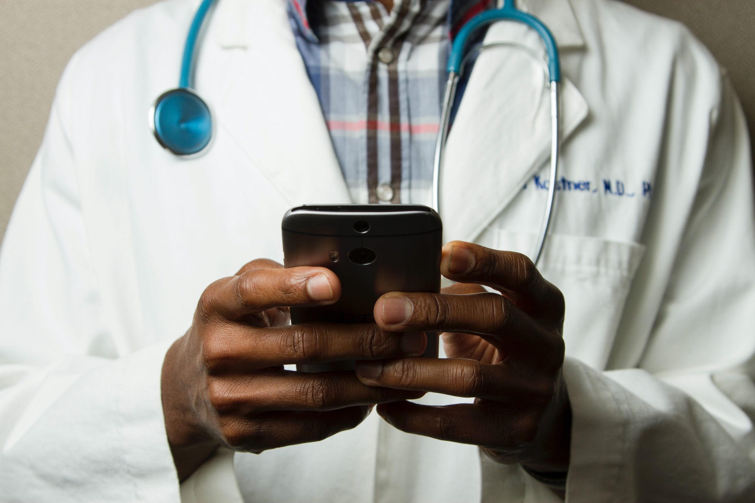 A healthcare professional is holding a smartphone in his hands