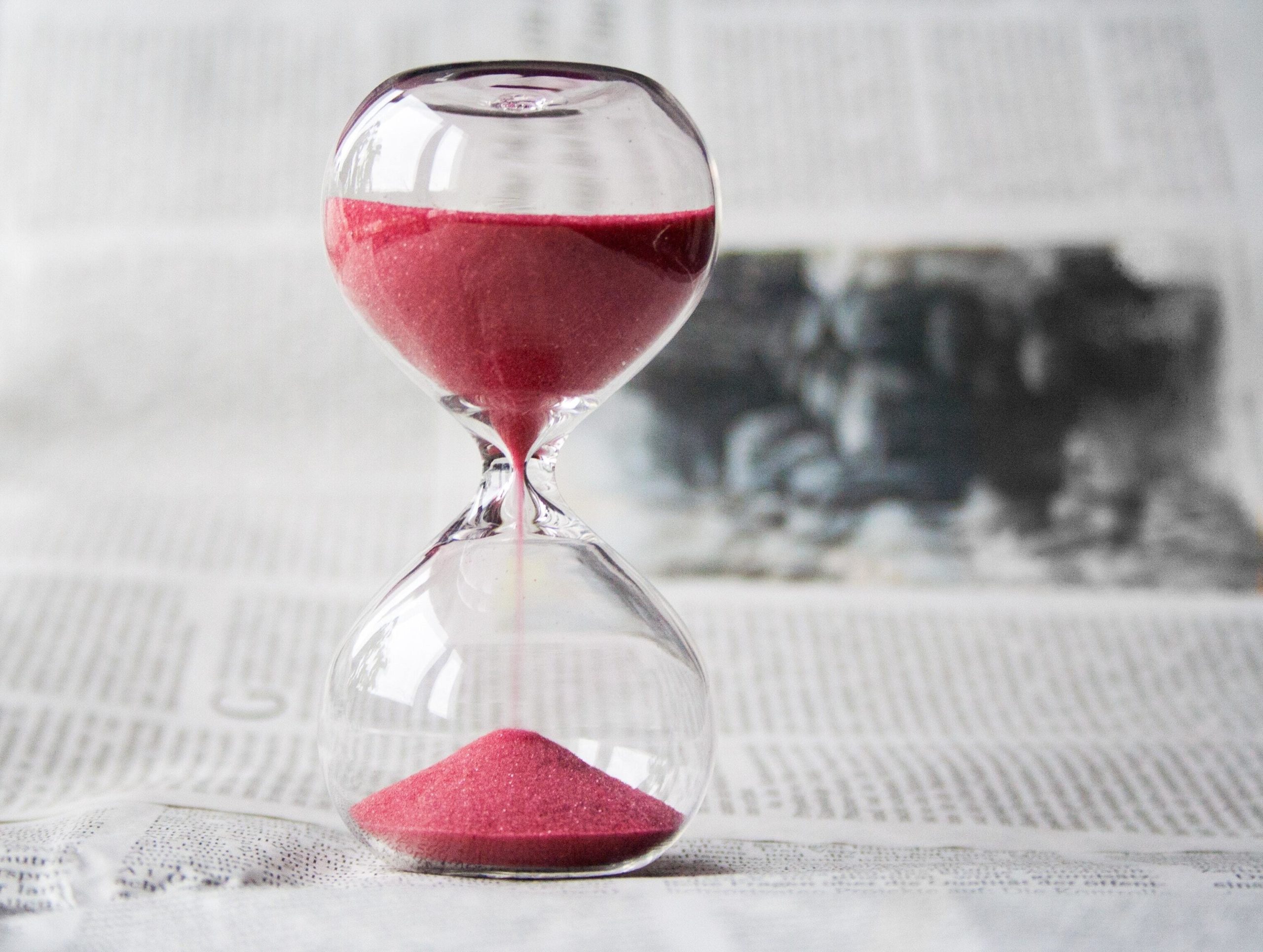 An hourglass is filled with pink sand